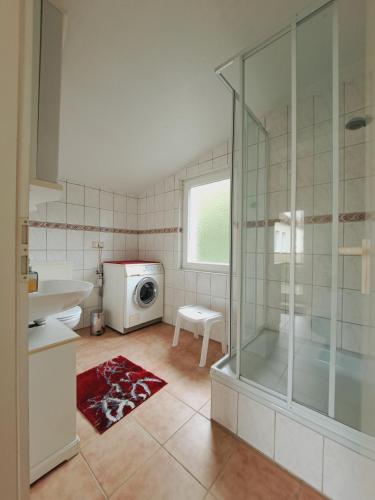 a bathroom with a shower and a washing machine at Heidtschmidhof Gästehaus in Wolgast