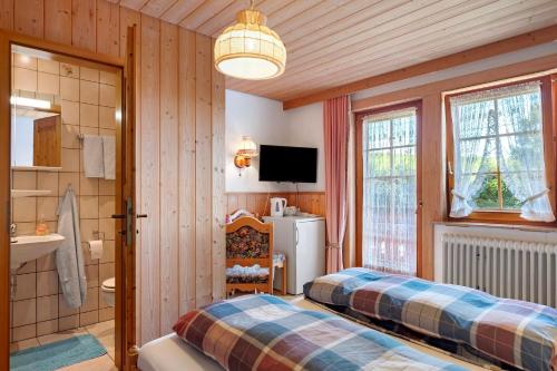 a bedroom with two beds and a refrigerator and a television at Willmannshof in Furtwangen