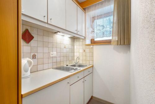 a small kitchen with white cabinets and a sink at Untersinnerhof Gsies in Valle Di Casies