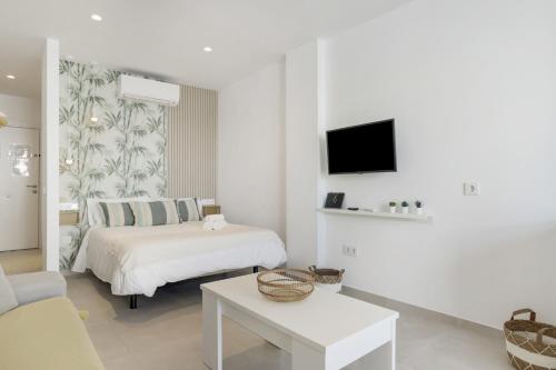 a white bedroom with a bed and a tv at Apartamento Bambú 2 10 in Tarifa