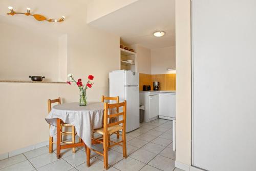 a kitchen with a table with chairs and a white refrigerator at Le Mas Berliat N°7 in Bormes-les-Mimosas