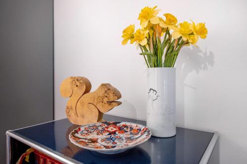a table with a vase and a plate and flowers at Eichhörnchens Paradies in Todtmoos