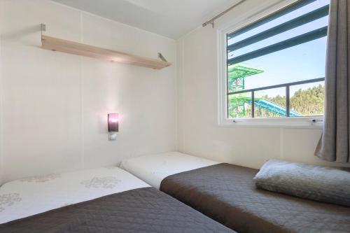 two beds in a room with a window at Bungalow T3 I V- 15 Min From Nazaré in Pataias