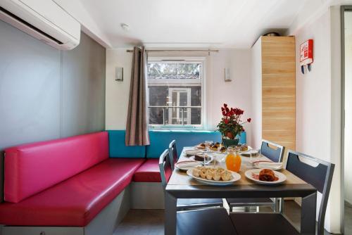 a dining room with a table and a red couch at Bungalow T3 I V- 15 Min From Nazaré in Pataias