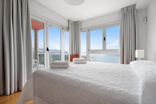 a bedroom with a large bed with large windows at Villa View Grand in Santa Úrsula