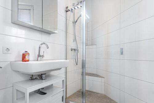 a white bathroom with a sink and a shower at Speicherapartment in Warendorf