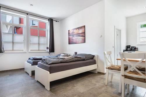 a bedroom with two beds and a table and windows at Speicherapartment in Warendorf