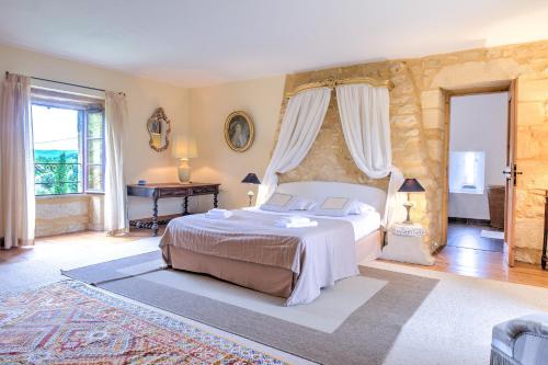 a bedroom with a bed and a table and windows at La Bourgeoisie in Domme