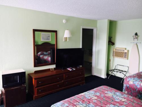 a hotel room with a bed and a dresser and a mirror at Relax Inn in Folkston