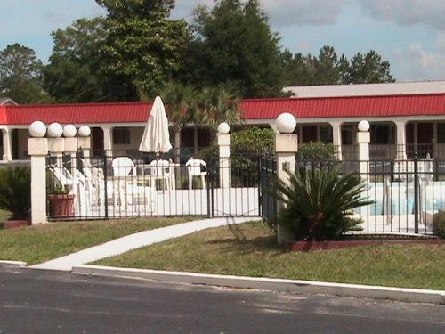 a building with a white fence and a umbrella at Relax Inn in Folkston