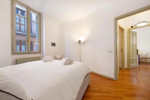 a white bedroom with a bed and a large window at Viasambuco in Iseo