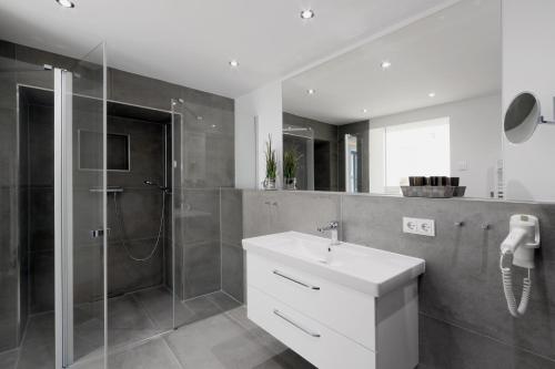a bathroom with a white sink and a shower at Gardensuite Binz in Binz