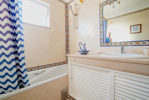 a bathroom with a sink and a tub and a mirror at Sunset Villa in Ferragudo