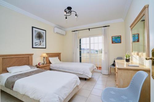 a hotel room with two beds and a desk and a window at Sunset Villa in Ferragudo