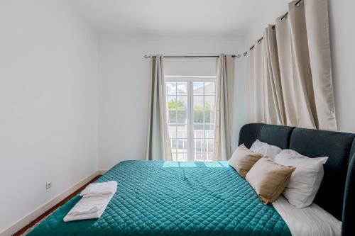a bedroom with a green bed with a window at Alojamento Local Coruche Erra in Coruche