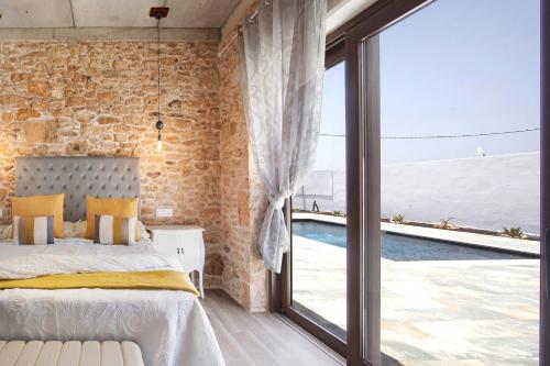 a bedroom with a stone wall and a bed and a large window at Casa Rural Berrenda in Tiscamanita
