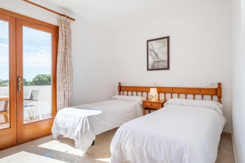 two beds in a room with a window at Apartamentos Karin 2ºd in Cala d´Or