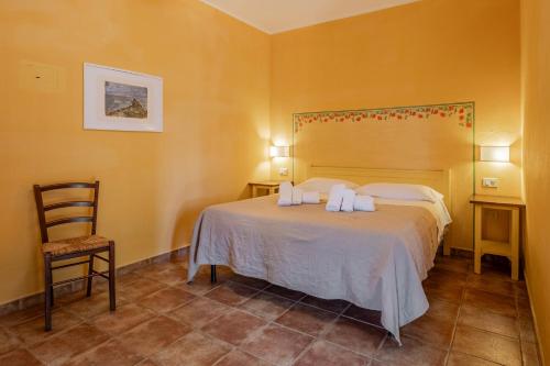 a bedroom with a large bed and a chair at Rosaspina - Appartamento 4 in Capalbio
