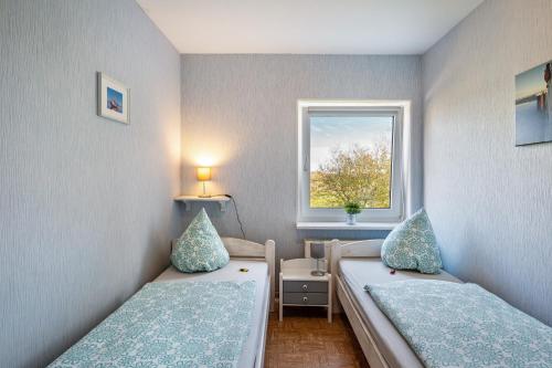 a small room with two beds and a window at Ferienhof Dethlefsen in Pellworm