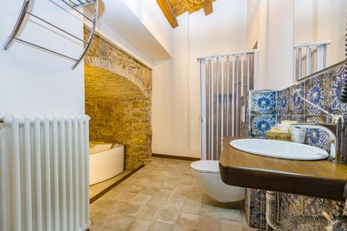 a bathroom with a sink and a toilet and a tub at Arcaloro Resort Rooms in SantʼAngelo di Brolo