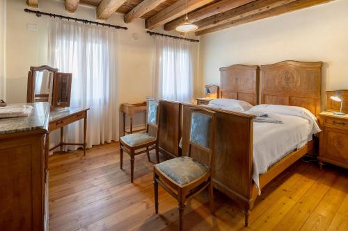 a bedroom with a bed with a desk and chairs at Agriturismo Marzanino in Torre di Mosto