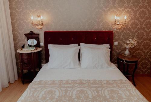 a bedroom with a bed with white sheets and two tables at Fonte do Pinheiro Boutique in Ponte de Lima
