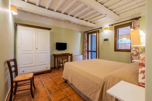 a bedroom with a bed and a desk and a tv at Rosaspina - Appartamento 2 in Capalbio