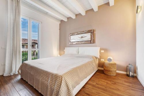 a white bedroom with a bed and a window at Appartamento Castello a Raffa in Puegnago