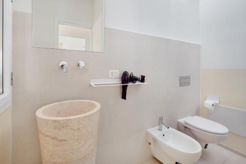 a white bathroom with a toilet and a sink at Cormorani - Appartamento 8 in Golfo Aranci