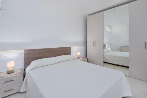 a bedroom with a white bed and a mirror at Cormorani - Appartamento 8 in Golfo Aranci