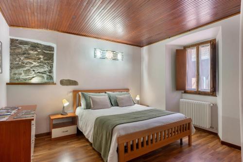 a bedroom with a bed and a wooden ceiling at Il Vicolino in Pettenasco