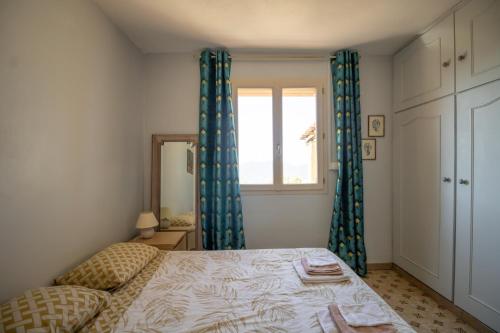 a bedroom with a bed with blue curtains and a window at Mon nid d'aigle in Olmeto