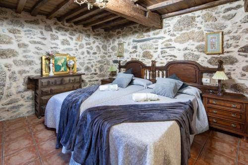 a bedroom with a large bed and a stone wall at Casa La Calleja in Arzúa