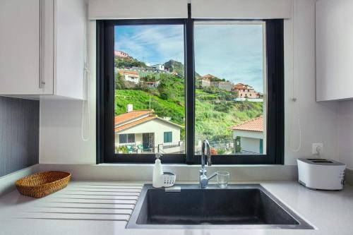 a kitchen with a sink and a large window at Apartamento Eden in Machico