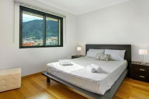 a bedroom with a large bed with a large window at Apartamento Eden in Machico