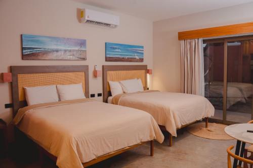 a hotel room with two beds and a window at Hotel Calma Celesti in Perihuete