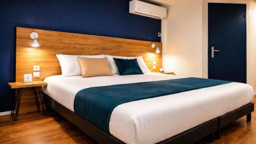 a bedroom with a large bed with a blue wall at The Originals City, Hôtel Mâcon Sud in Chaintré