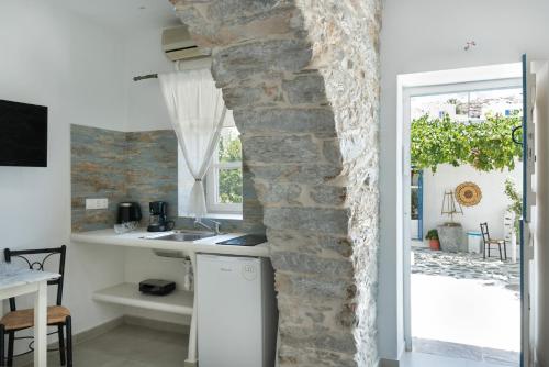 a kitchen with white counters and a stone wall at Politimis Studio N6 in Amorgos