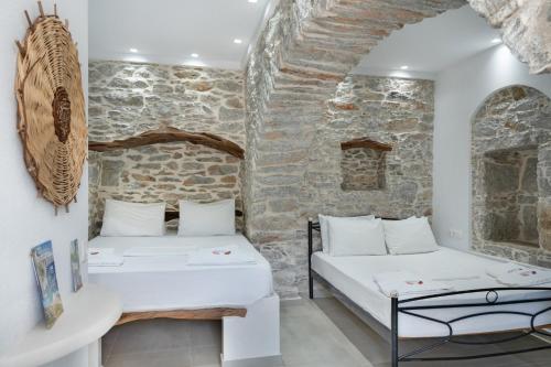 two beds in a room with a stone wall at Politimis Studio N6 in Amorgos