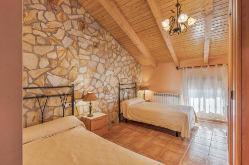 a bedroom with two beds and a stone wall at El Ático in Maluenda