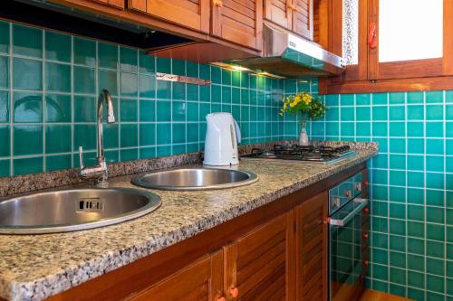 a kitchen with two sinks and green tiles at Pentavano White House in Isola Rossa
