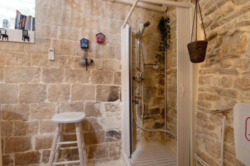 a shower with a stool in a stone bathroom at La Cantina in Giovinazzo