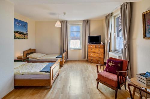 a bedroom with two beds and a tv and a chair at Bachmanns Ferienwohnung 2 in Schotten