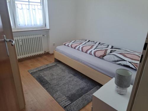 a bedroom with a bed with a rug and a window at Ferienwohnung im Ries in Wallerstein