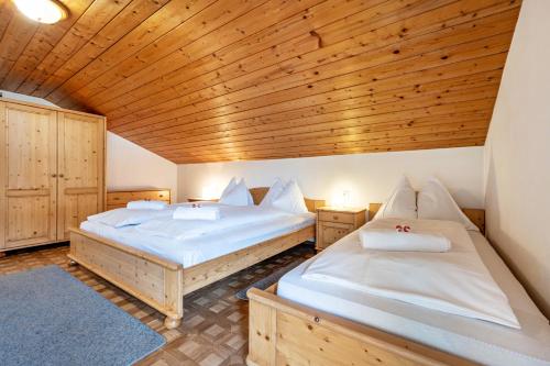 two beds in a room with a wooden ceiling at Manuel's App Watschinger - Enzian in Sesto