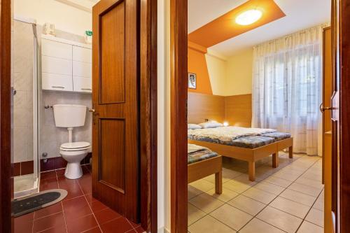 a bathroom with a toilet and a bed in a room at Appartamento Alexander in Tignale