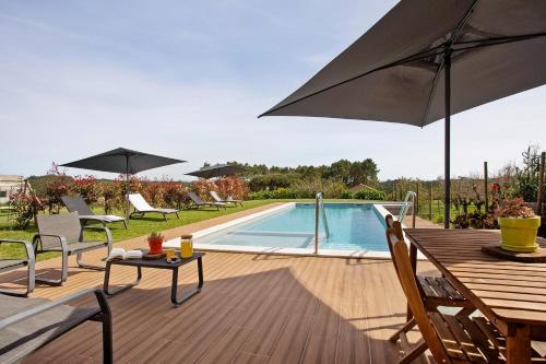 a patio with a table and an umbrella and a pool at Quinta dos Raposos- Nazaré Portugal in Nazaré