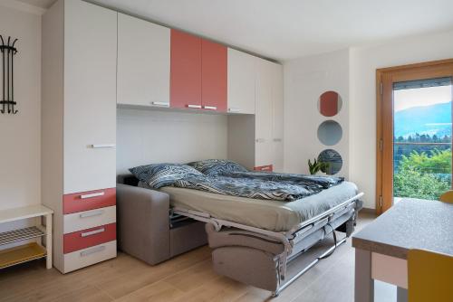 a bedroom with a bed with red cabinets and a window at Maso Plocech App Vacanze in Pergine Valsugana
