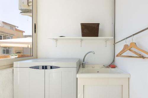 a white kitchen with a sink and a mirror at Max Apartment in Quartu SantʼElena