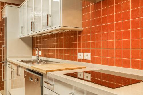 a kitchen with white cabinets and orange tiles on the wall at Villa Happy Dreamer in Puerto Rico de Gran Canaria